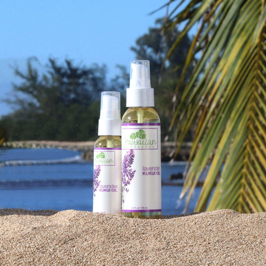 to bottles of lavender kukui oil set on the sand with the beach in the background